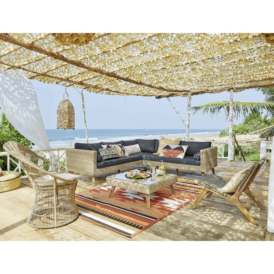 Los muebles de ratán, el bambú y los tejidos rústicos dan forma a salones de exterior tan bonitos como este de Maison du Monde.