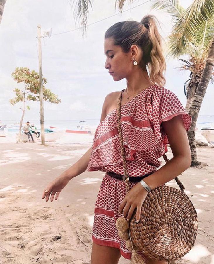 María Pombo ha decidio enseñar en esta fotografía dos tendencias clave para este verano, el bolso redondo de rafia y su vestido con estampado palestino, de estilo boho y con escote asimétrico.