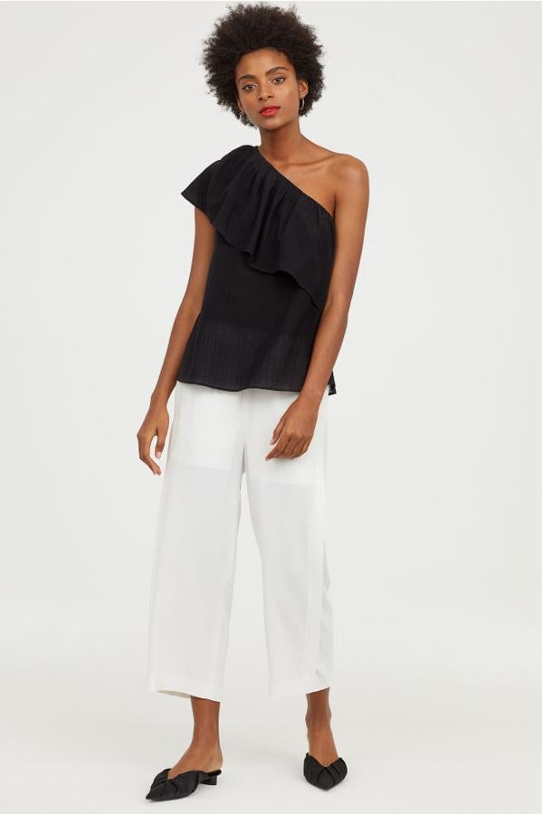 Top de con escote asimétrico y volante en color negro, 14,99 euros.