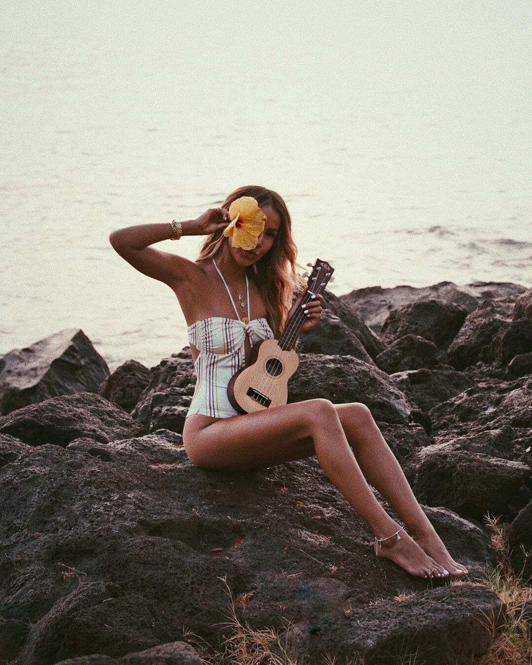 Julie Sariñana en Maui. No se pueden interpretar mejor las señas de identidad hawaianas: ukelele y flores tropicales. El bañador de inspiración setentera, con ese escote taaaan bonito, es de Tularosa.