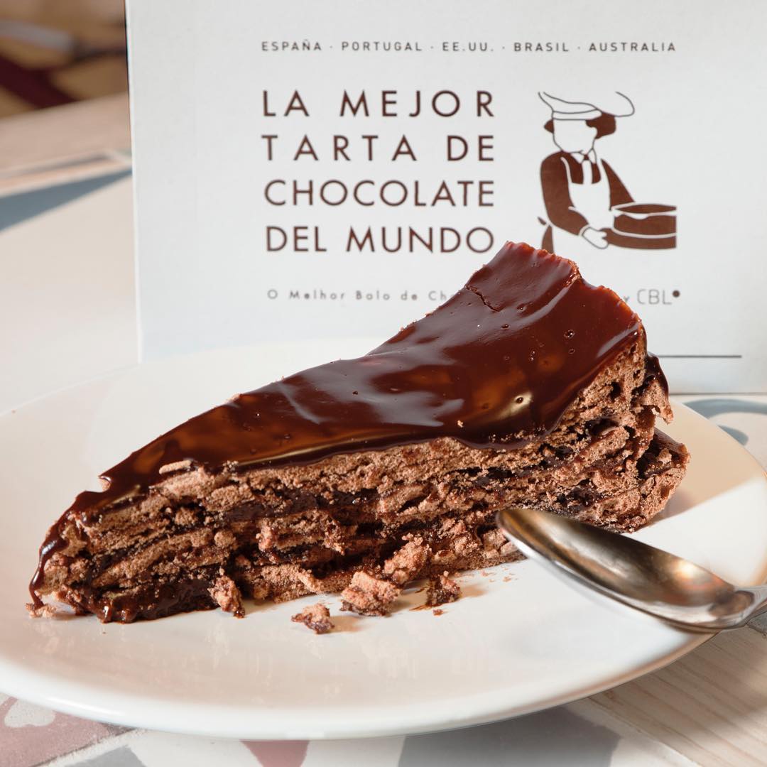 Chocolate, mantequilla, margarina, azúcar, cacao en polvo y huevo son los ingredientes de la icónica tarta de chocolate (y valga la redundancia) de La mejor tarta de chocolate del mundo. Ya solo con ver esta fotografía podemos intuir porqué se ha convertido en la tarta más famosa de Madrid.Calle Alcala, 89 (Madrid).