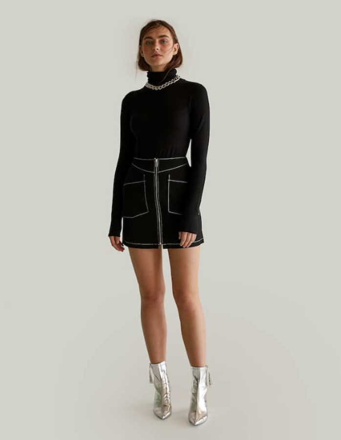Este total look negro nos encanta: falda midi con cierre cremallera (15,99 euros) y jersey de cuello cisne (12,99 euros). Merece la pena saltarse un poco el presupuesto inicial para añadir esos fantásticos botines plateados (35,99 euros).