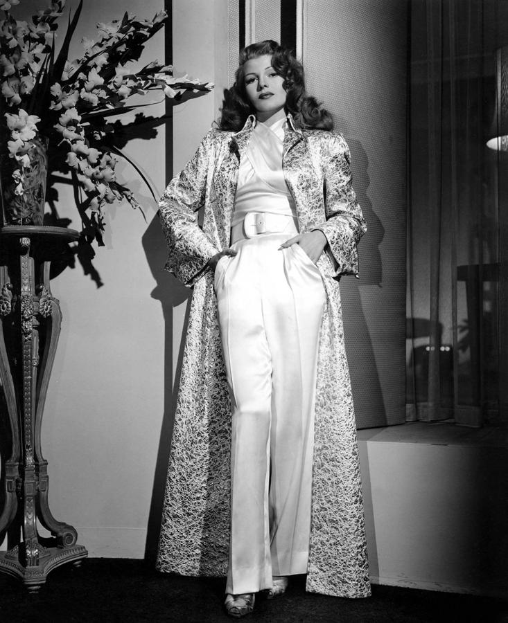 Si solo pudiéramos quedarnos con un look de Rita Hayworth, con permiso de su vestido icónico en 'Gilda', sería con este conjunto de traje pantalón y abrigo joya brocado. Y con su actitud al posar ante la cámara...