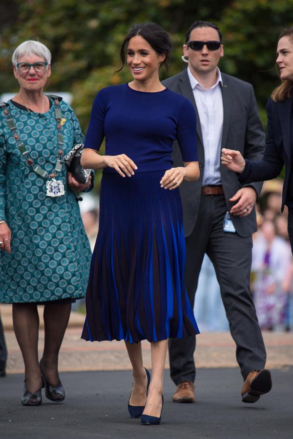 Meghan Markle ha hecho del azul 'navy' su color oficial de este viaje, como ha vuelto a demostrar con este look con falda plisada que nos recuerda mucho a estos  vestidos de Hugo Boss de la Reina Letizia .