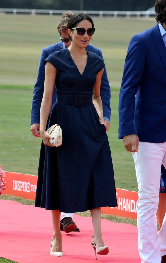 Meghan lleva un vestido con corte tipo lady con cinturón ancho y en color oscuro. El toque con las gafas de sol XL nos encanta.