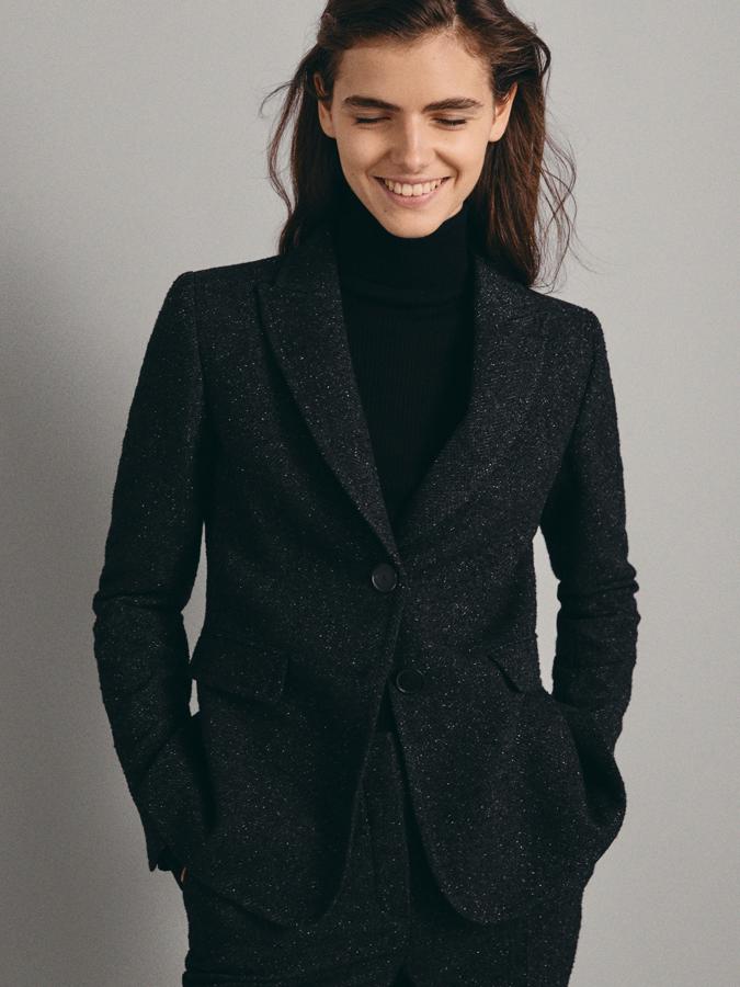 Americana negra con estructura de espiga jaspeada y cierre con dos botones (75,95 euros) y pantalones slim con cierre de corchetes y cremallera oculta a juego (59,95 euros).