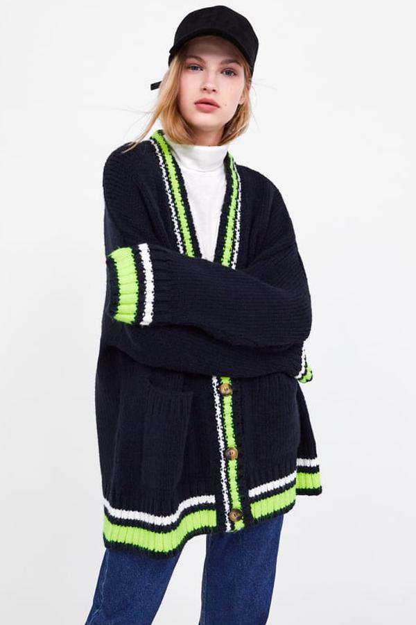 Cárdigan amplio de punto grueso, con acabados en "rib" en contraste blanco y fluor y bolsillos frontales (Zara, 29,95 euros).