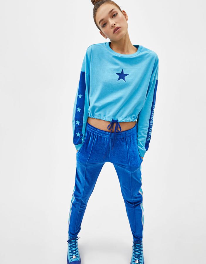 Con cuello redondo, manga con banda lateral de estrellas y logo combinada a contraste y cordón ajustable en bajo (45 euros).