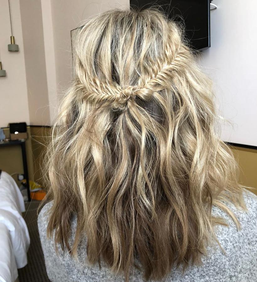 ¿Te atreves con un look un poco más complicado? Tras ondular tu melena, hazte una trenza de raíz en la parte superior derecha y otra en la izquierda. Sujétalas con un par de gomas muy pequeñas y después anúdalas. Termina abriendo un poco el trenzado y ¡voilà!