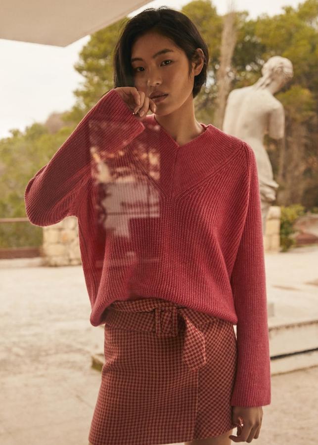 Mini falda en tejido de algodón con trabillas en la cintura y cinturón ajustable y desmontable (29,99 euros) y jersey de punto de canalé con escote de pico y manga ranglán (29,99 euros).