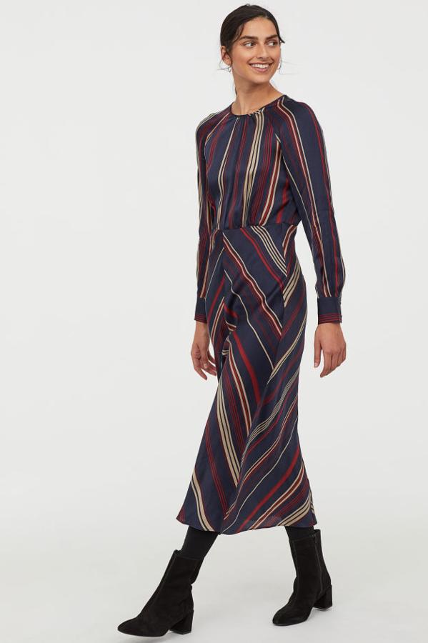 Vestido con escote redondo y fruncidosen la parte delantera. Lleva costura en la cintura, mangas raglán largas con botones revestidos en los puños y va sin forrar (49,99 euros).