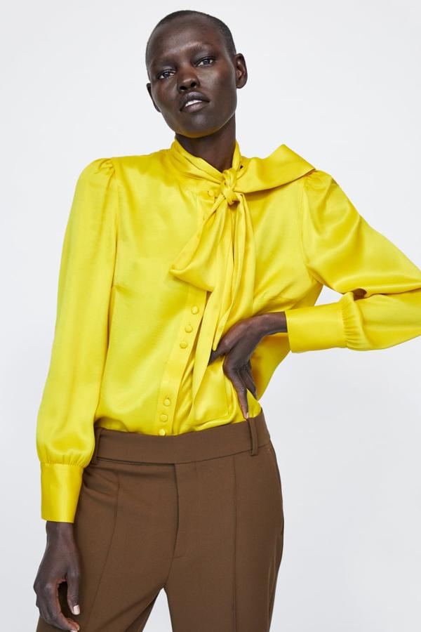 Blusa fluida de cuello subido con lazo y cierre delantero con botones forrados (Zara, 29,95 euros).