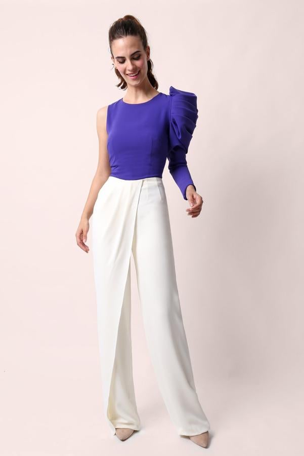 Top confeccionado en crepe con cuello caja, espalda cerrada y diseño simétrico con una sola manga larga abullonada (164,50 euros), pantalón largo confeccionado en crepé con sobre falda lateral sobre una pata del mismo (189 euros).