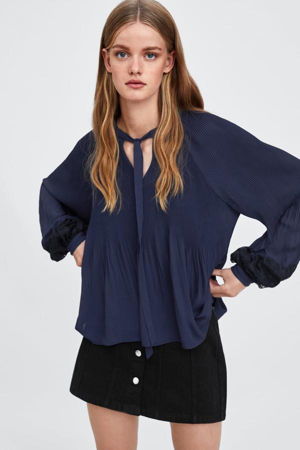 Camisa plisada con cuello redondo, manga larga abullonada y cierre delantero con lazada, 17,99 euros.