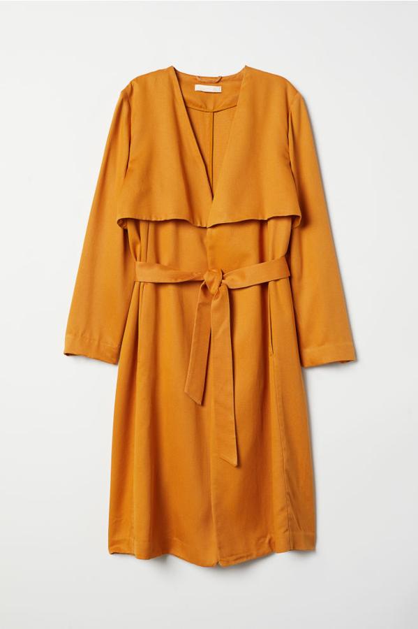 Gabardina de lyocell en color mostaza y con abertura trasera, 29,99 euros.