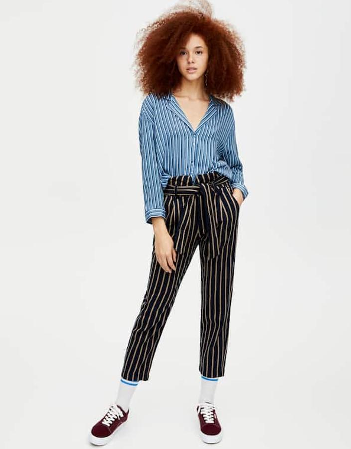 Nos chifla esta combinación de rayas que no tienen nada que ver: las de los pantalones de cintura "paper bag" y cinturón en negro y beis (22,99 euros) y las de la camisa, azules y blancas (15,99 euros).