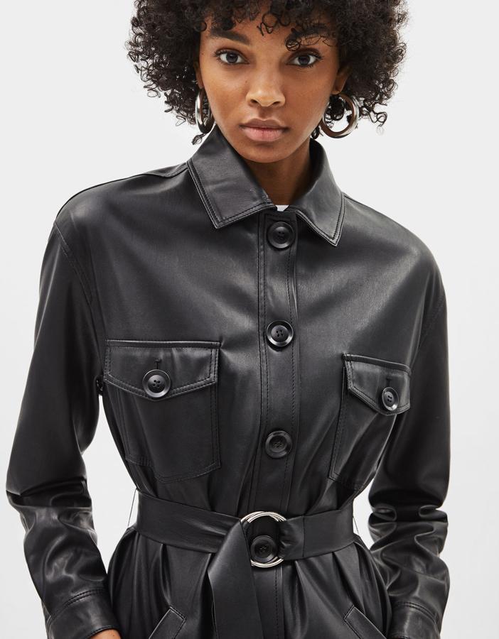 Sobrecamisa efecto piel con cinturón en el mismo tejido y hebilla metálica. Lleva cuello solapa, bolsillos en la parte delantera, cierre abotonado y bajo asimétrico (39,99 euros).
