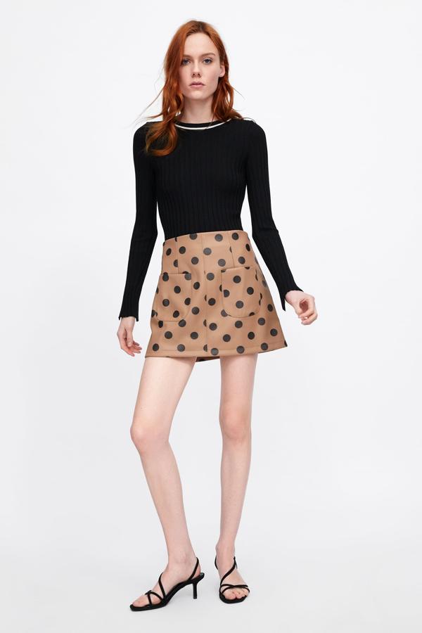 De inspiración retro, esta mini falda efecto piel en color café con lunares negros en contraste es de Zara y cuesta 19.95 euros.
