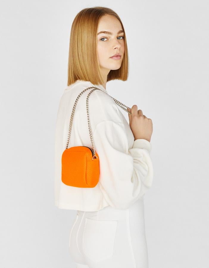 Si eres 'pequeña' de estatura, olvídate de los maxi bolsos que parecen más grandes que tú y apuesta por modelos mini como este neón de Bershka (12.99 euros).