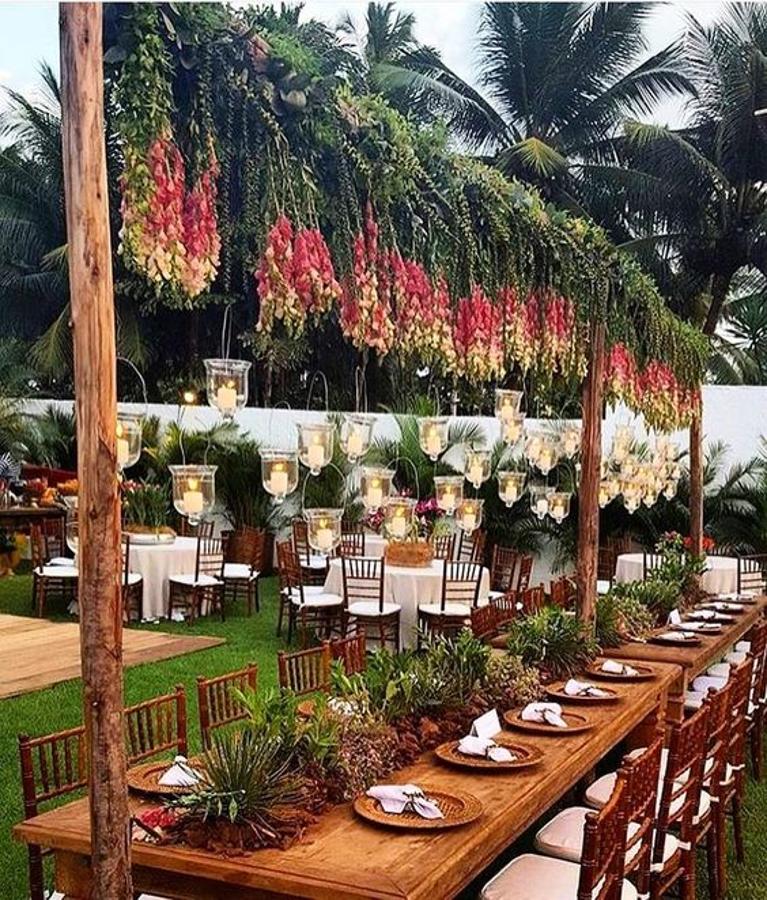 Las luces, las flores y plantas de temporada, las mesas infinitas y el estilo 'rustic chic' se adueñan de la decoración exterior de esta boda al aire libre.