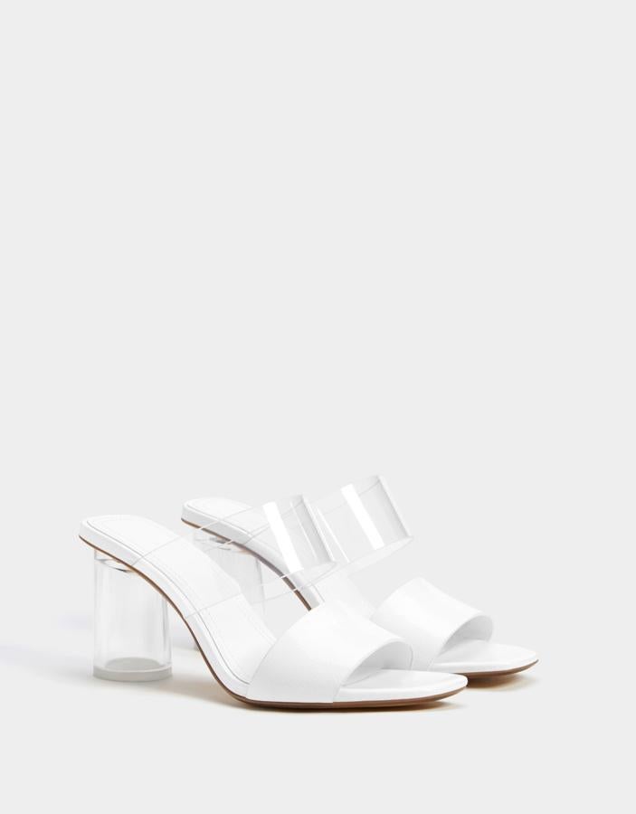Sandalias destalonadas en blanco con detalle de tira transparente en el empeine, de Bershka (27.99 euros).