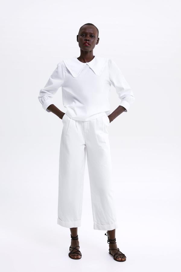 En un look 'total white' con una blusa de inspiración 'naive' como esta (29.95 euros en Zara).