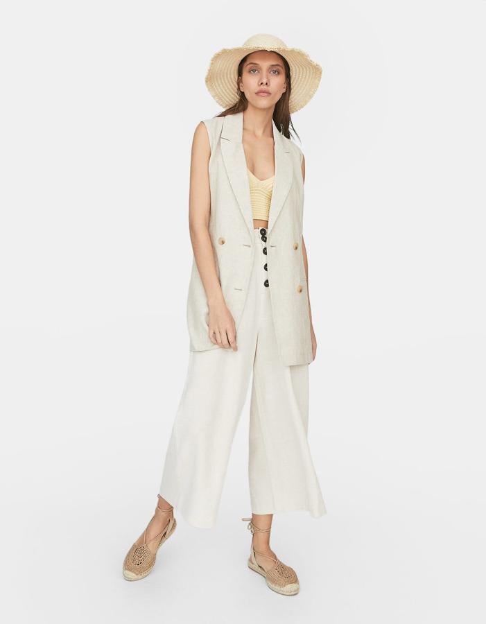 ¿Puede ser más ideal y sofisticado este conjunto en blanco roto? El chaleco de lino 'oversize' cuesta 35.99 euros, y los pantalones culotte con botones en contraste, 19.99 euros.