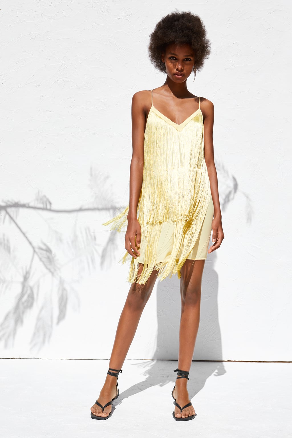 Vestido mini con flecos a lo charlestón en tono amarillo pastel, perfecto para tu próximo bronceado. (29,95 euros).