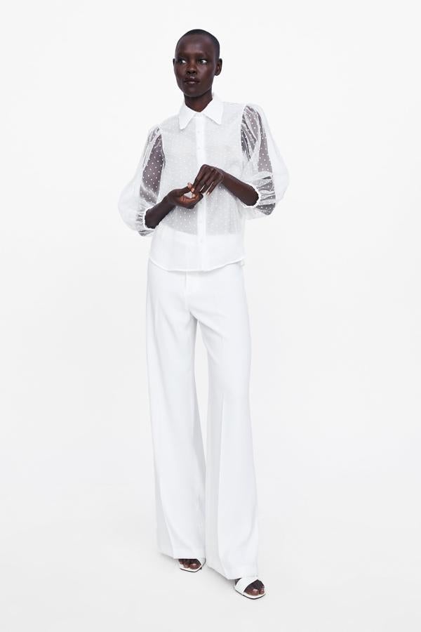 Delicada blusa de plumetti con transparencias y lunares en blanco (29.95 euros en Zara).