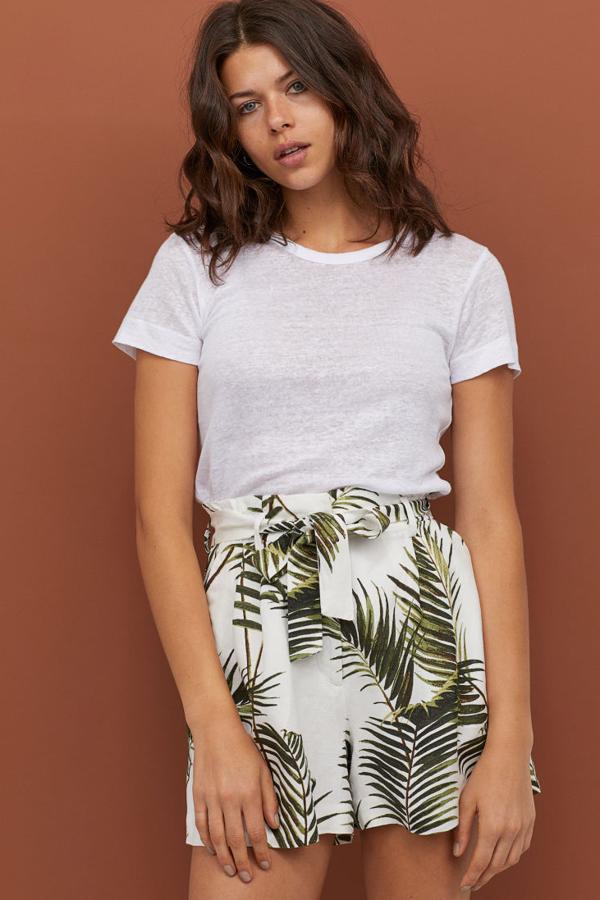 Pantalón corto en tejido vaporoso de lino y viscosa. Lleva el talle alto con cintura abullonada y un elástico detrás, pliegues en la parte superior y cinturón de anudar extraíble (19,99 euros).