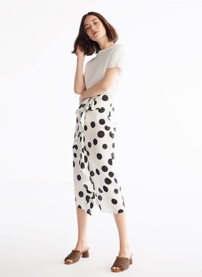 Los lunares son tendencia. Y en la firma de Inditex los llevan a su máximo tamaño en esta falda con volante delantero, perfecto y estratégico para tapar la tripita. Tienen el top a juego pero la puedes llevar con uno negro de manga abullonada y quedará ideal (79 euros).