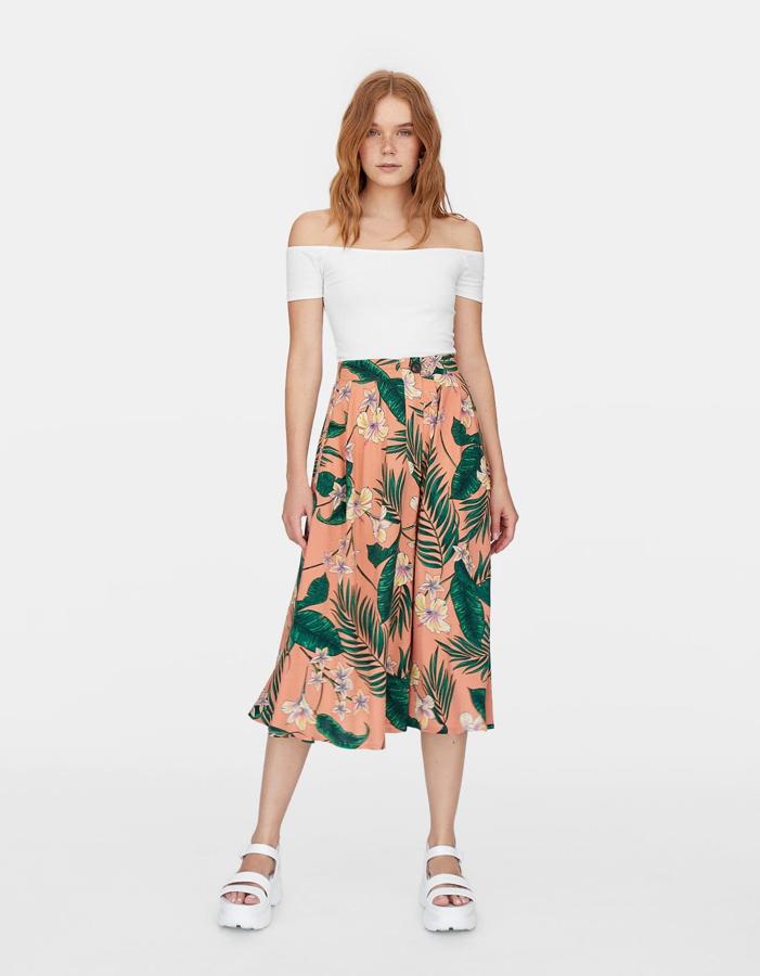 Falda con bolsillos laterales de estampado tropical con fondo rosa, de vuelo y cierre delantero (25,99 euros).