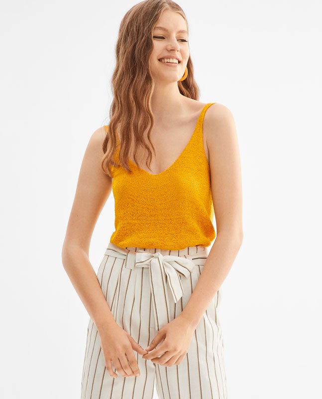 De silueta amplia, tirante y escote pronunciado, en un favorecedor color amarillo en tejido rústico. Es de Lefties y cuesta 12.99 euros.