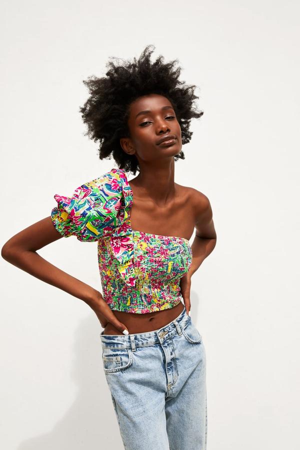 Cuerpo corto de escote asimétrico y manga corta abullonada, en tejido tipo nido de abeja. lleva el adorno de un volante en el hombro (19,95 euros).