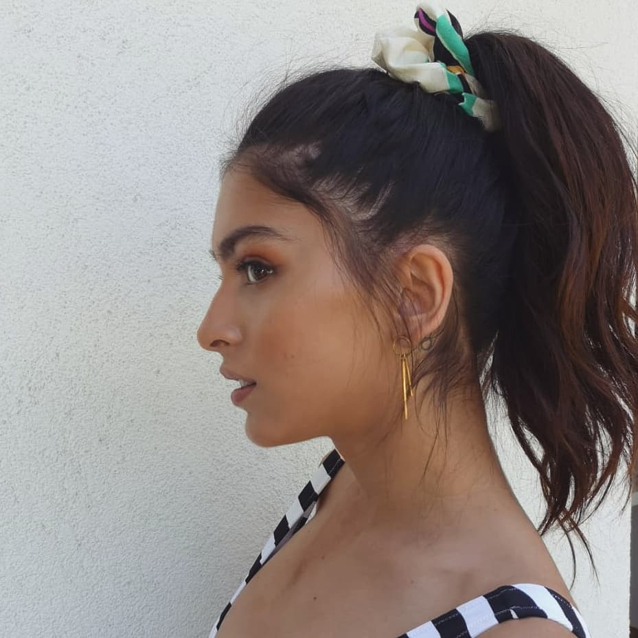 La coleta alta es un peinado fácil y clásico que nunca falla. Transfórmala hacia un estilo más messy como la de Lucía Rivera soltando algunos mechones delanteros y ondulando un poco las puntas. Utiliza un coletero noventero para darle el toque final.