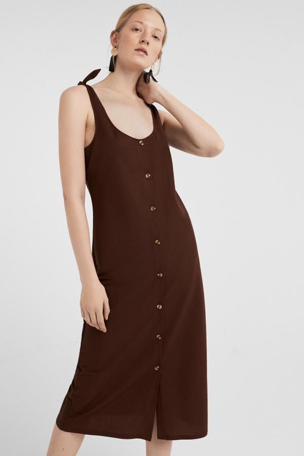 No te compliques la vida y apuesta por cortes sencillos y fresquitos como un simple vestido de tirantes con botonadura fronta. Este tiene un tono marrón chocolate, costaba 25,99 euros y ahora se ha quedado en 19,99 en la rebajas de Springfield.
