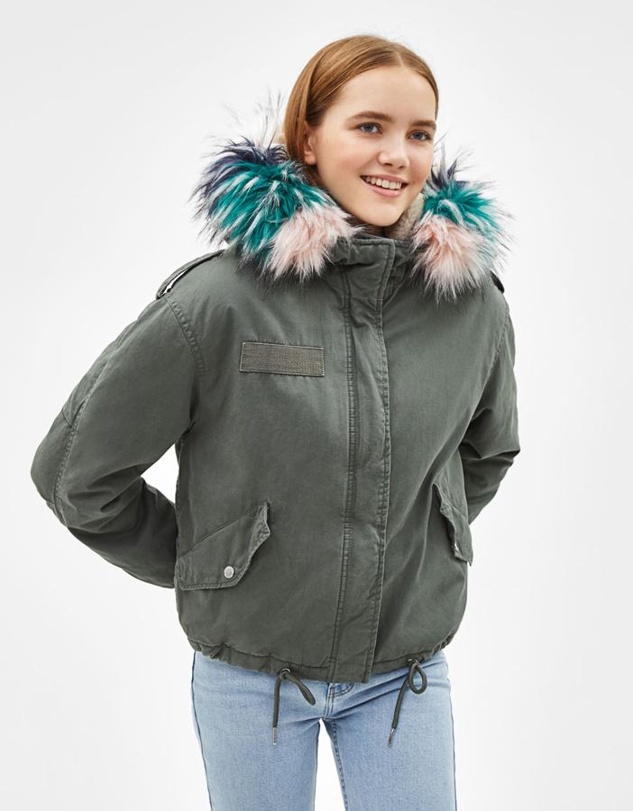 Cazadora corta con interior forrado con tejido efecto pelo, detalle de color en el interior. Lleva bolsillos laterales, cierre de cremallera, cintura ajustable y pelo en capucha extraíble (Bershka, 24,99 euros).