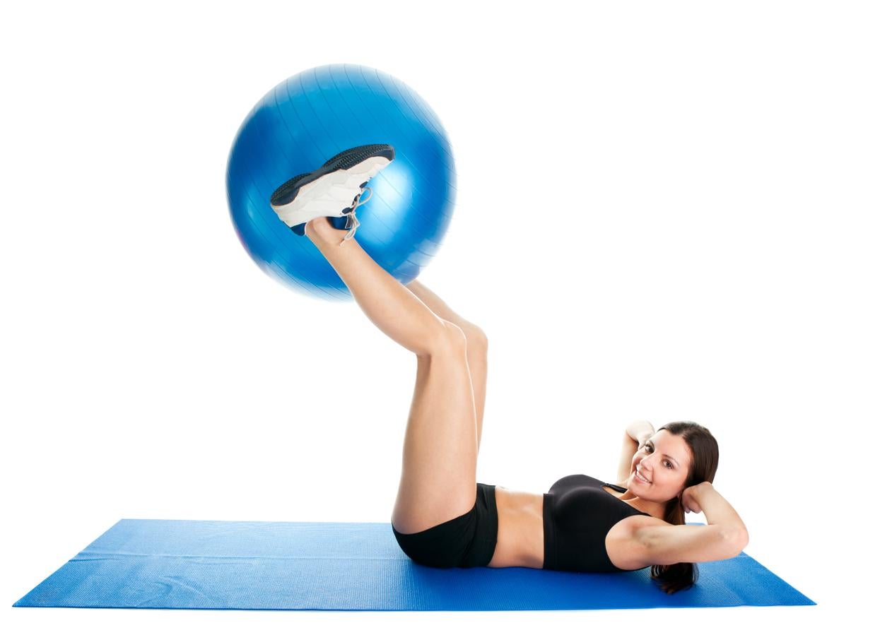 Con la 'fitball' entre las piernas y manteniéndolas en alto, lleva a cabo tu serie de abdominales oblicuos. Y haz tantas repeticiones como sea necesario.