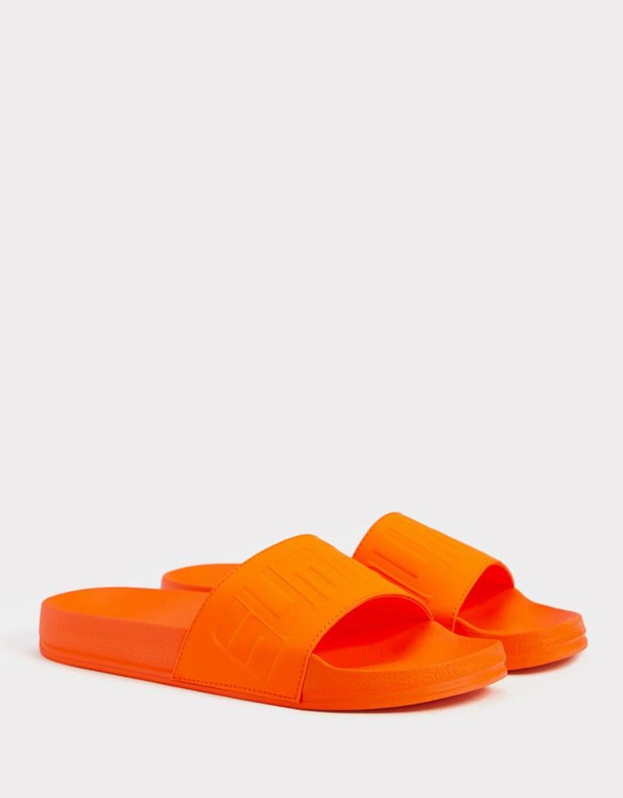 Sandalia monocolor en naranja neón, con detalle de texto en la pala (Bershka, 7,99 euros).