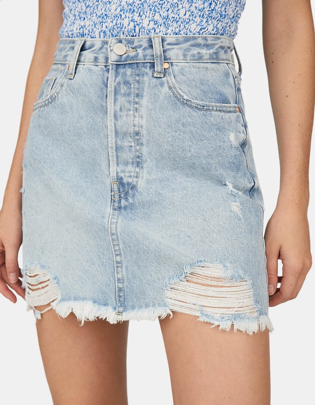¿Todavía no tienes una falda mini denim en tu armario? Esta con rotos de la nueva colección de Stradivarius va a elevar cualquier look de verano. (19,99 euros).