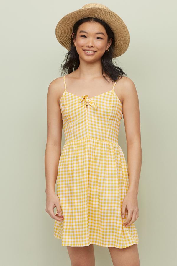 Mini vestido amarillo y blanco con estampado de cuadros vichy y detalle de lazo en el escote. En las rebajas de H&M pasa de 14.99 a 5.99 euros.