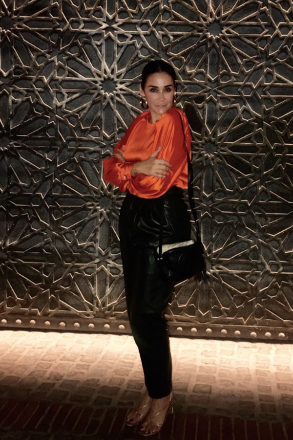 La sevillana combina el top naranja eléctrico de mangas abullonadas y con un detalle de botones joy en los puño con unos pantalones de cuero negro, apostando por un estilo retro que nos encanta.