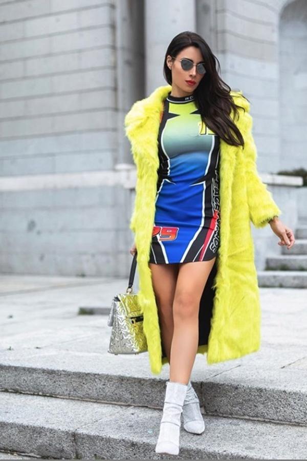 La prenda principal del look es un  enorme abrigo amarillo flúor  de la línea Sh by Silvian Heach. Largo, de pelo y con grades solapas, aspira a protagonizar absolutamente cualquier "outfit", pero aquí tiene dura compentencia. Empezando por los complementos: gafas con un ligero efecto espejo de Gigi Barcelona, un bolso acolchado en un plata espacial de Furla, unos botines con calcetín plateados de Steve Madden y el vestidos inspirado en los corredores de motos y de Fórmula 1.