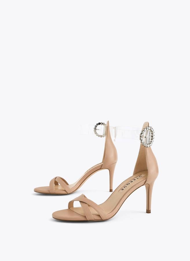Unas sandalias que realcen tu moreno y te hagan unas piernas de infarto, como estas nude con pulsera transparente y broche joya de Uterqüe (89 euros).
