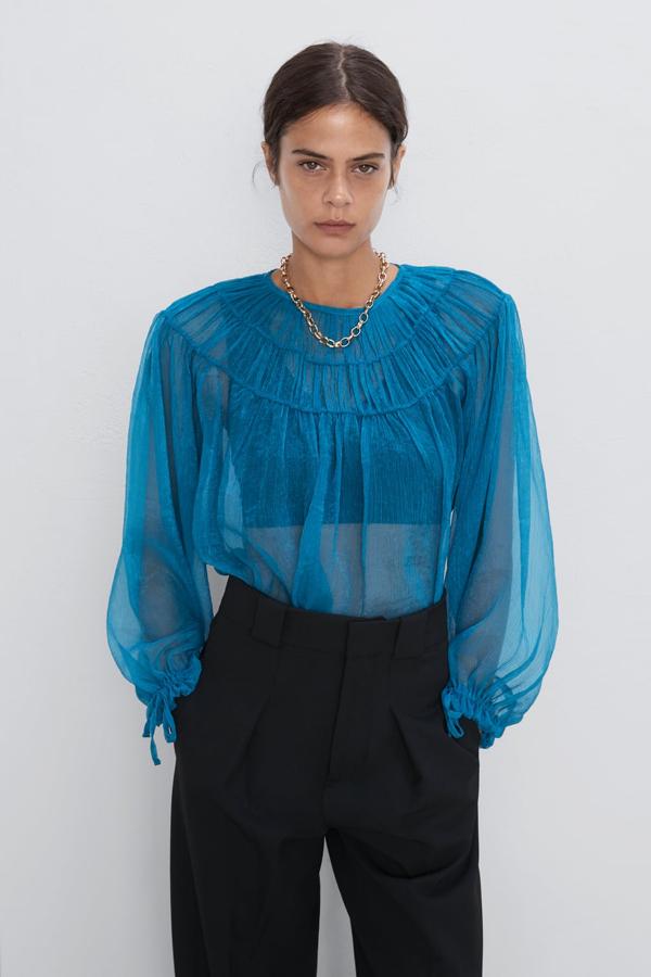 Blusa semitransparente con cuello redondo y mangas con puño ajustable en color turquesa, 19,95 euros.