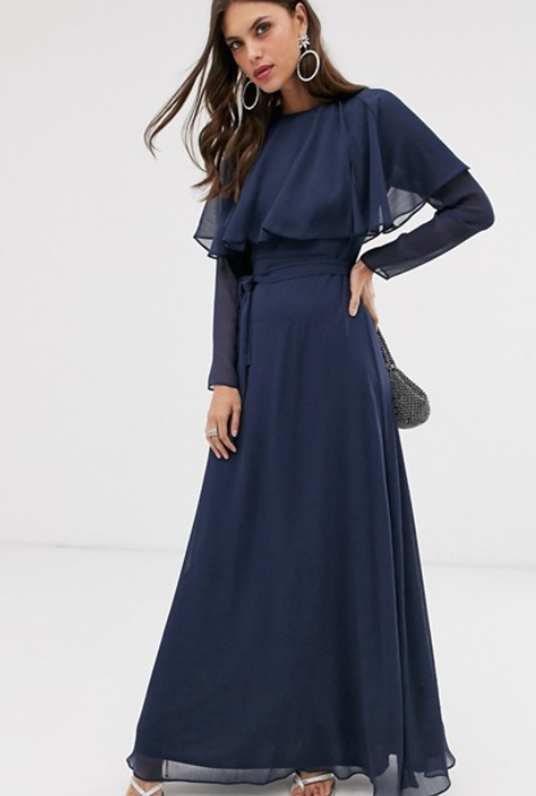 Vestido largo con capa en la parte posterior y lazo a la cintura de Asos Design (57,99 euros). Lleva cuello subido y cierra con una cremallera en la parte posterior.