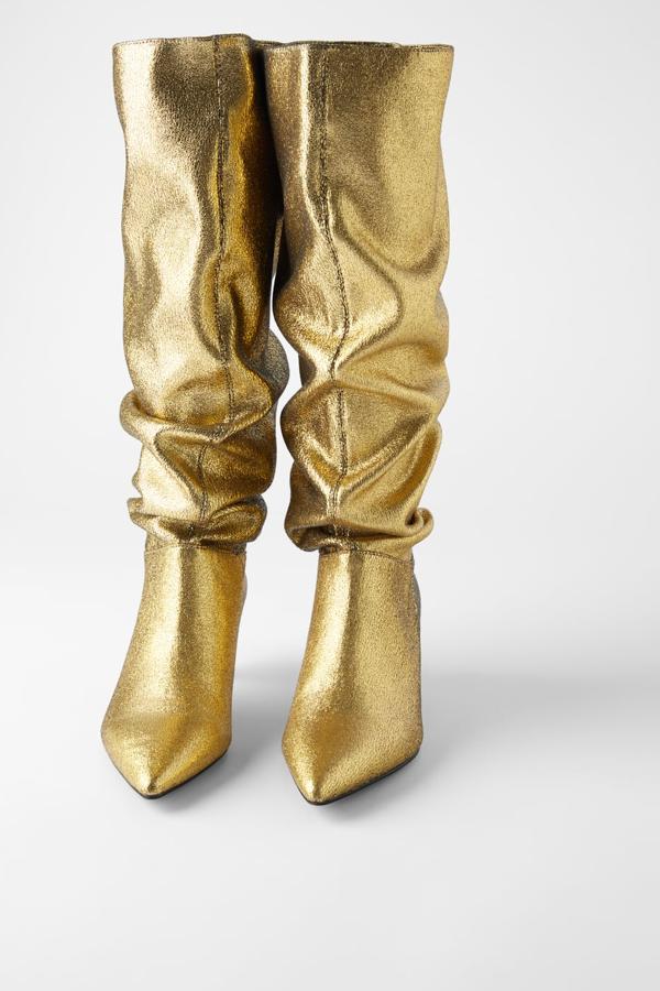 Bota de tacón de color oro metalizado, caña alta elástica y acabada en punta. Lleva un tacón kitten con una altura de 5.5 centímetros (Zara, 59,95 euros).
