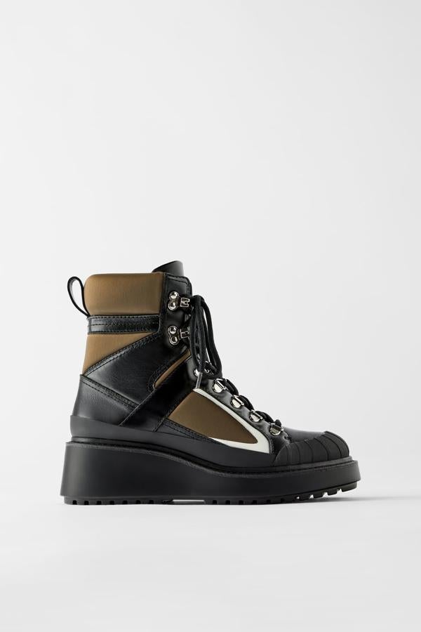 Botín plano en una combinación de negro, blanco y marrón y de distintos materiales. Lleva una pieza engomada de adorno en la parte delantera, collarín acolchado y tirador trasero. Cierra mediante cordones con pasadores metálicos y es de Zara (89,95 euros).