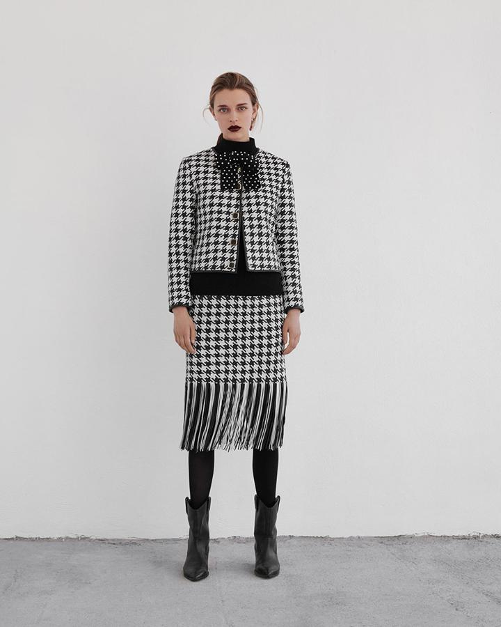 Otro traje de la nueva colección 'The Maze' Uterqüe que parece sacado del imaginario creativo de Chanel: el blanco y negro, el estampado pata de gallo, el patronaje... La chaqueta de piel trenzada cuesta 299 euros; y la falda a juego con detalle de flecos, 279 euros.