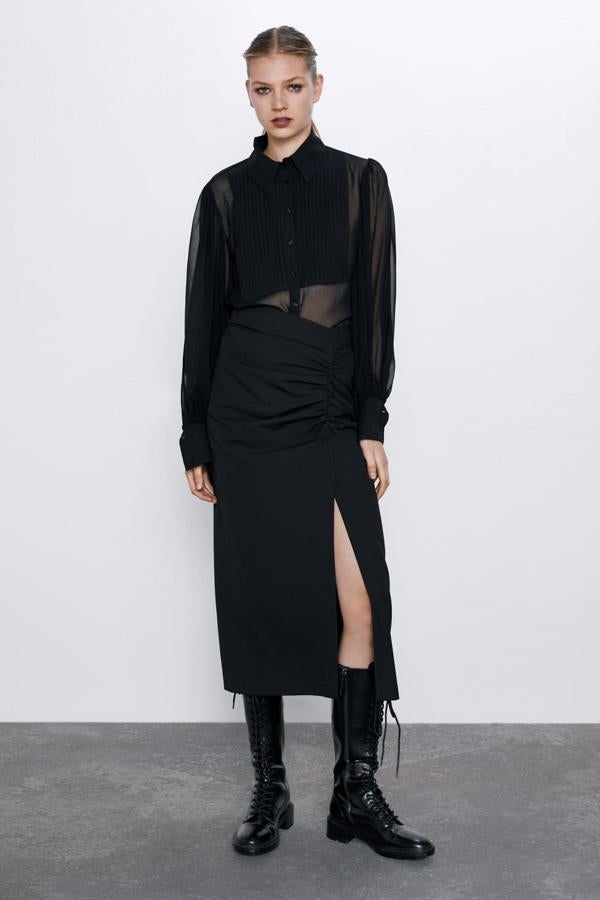 Blusa semitransparente con detalle de pliegues en delantero, cuello solapa y elástico en espalda tipo nido de abeja (Zara, 39,95 euros). Falda midi de tubo y tiro alto, con con abertura delantera en el bajo y cierre lateral con cremallera oculta en la costura (Zara, 29,95 euros). Bota plana de piel de color negro con cordones, punta cuadrada y tirador trasero (Zara, 99,95 euros). Lleva una suela gruesa tipo track y cierra con una cremallera interior.
